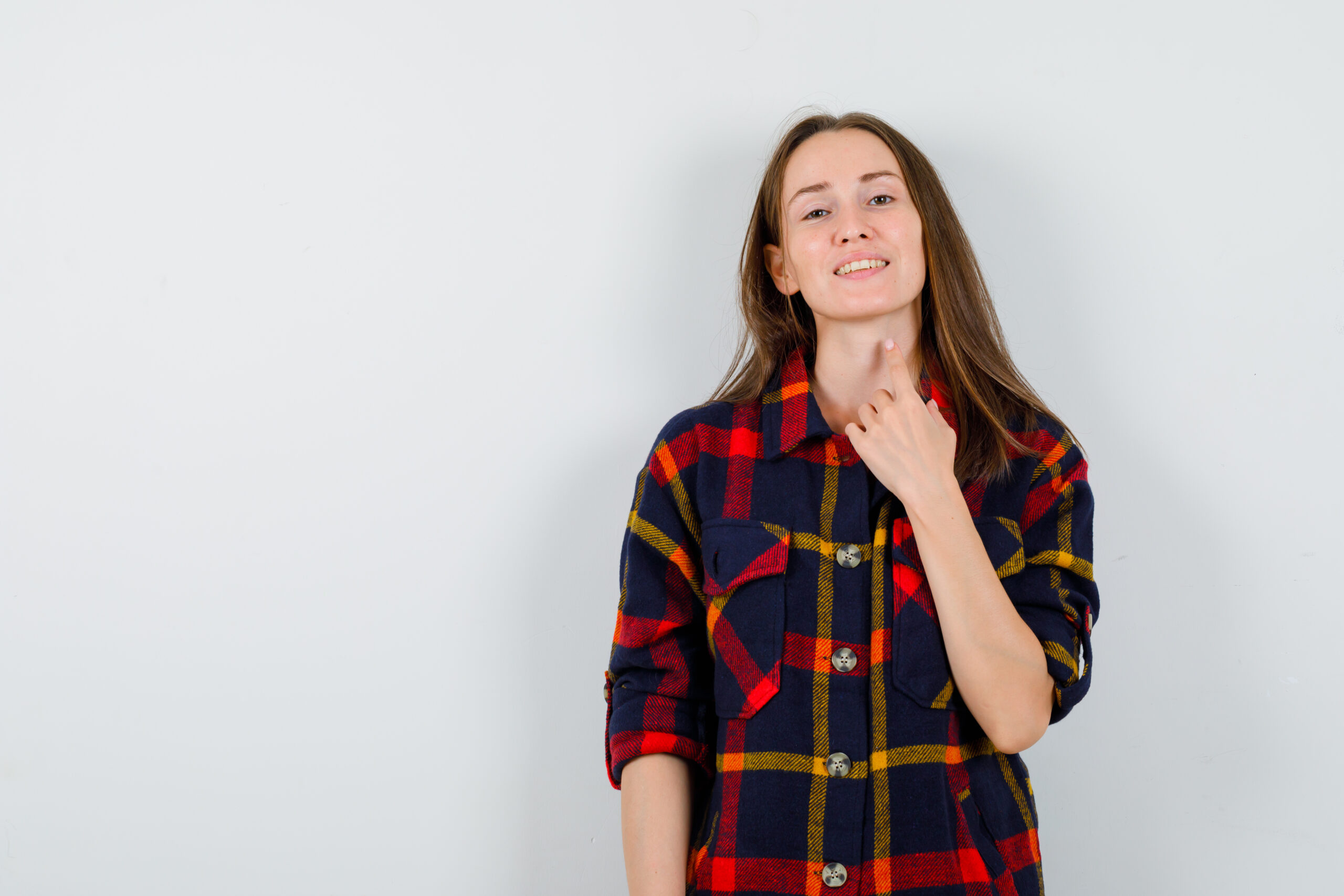 Portrait of young lady touching her neck with finger in casual shirt and looking jolly front view
